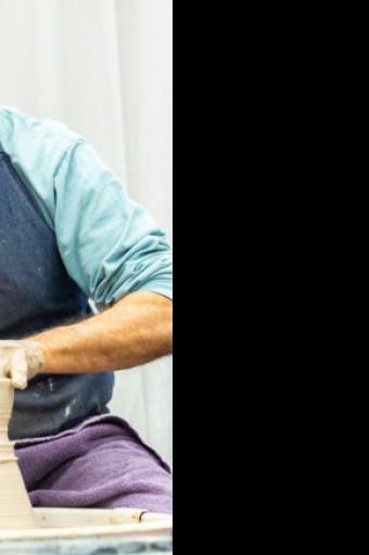 Man creating clay pot on potters wheel
