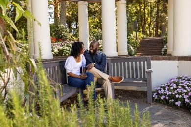 A man and woman sit on a park bench together at Reynolda Gardens.