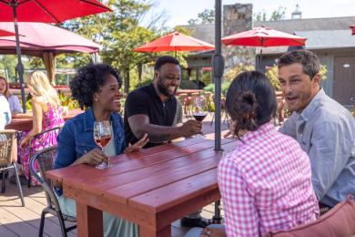 Four people sit at an outdoor dining table at JoLo Winery & Vineyard's Endposts Restaurant near Winston-Salem.